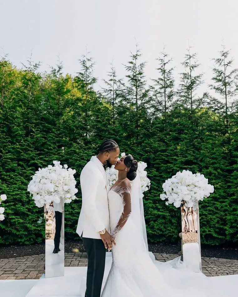 A couple kissing between white floral pedestals