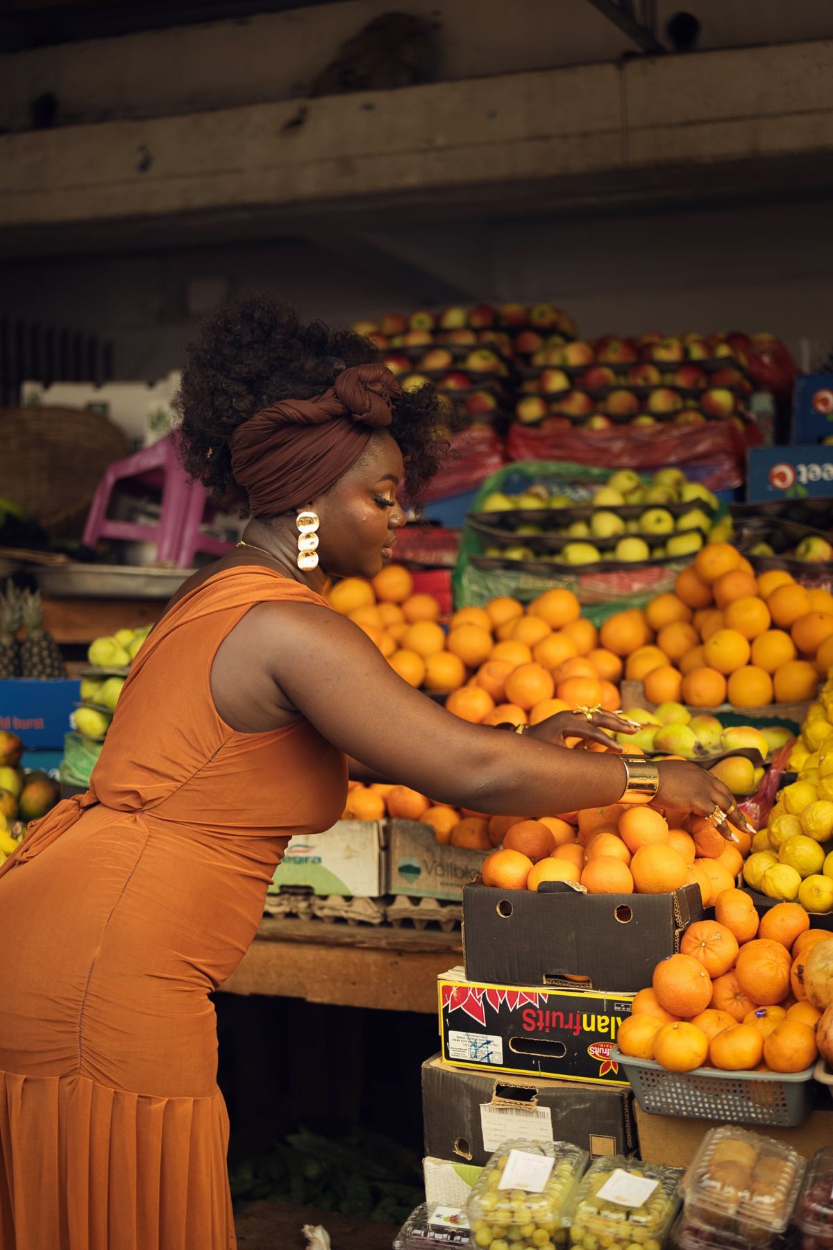 A shopper choosing oranges at a fruit stall