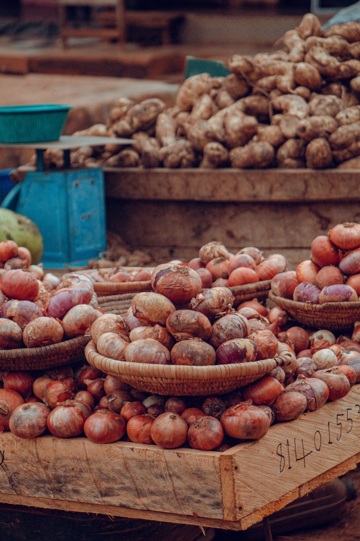 Yams and red onions stacked in crates at a market stall