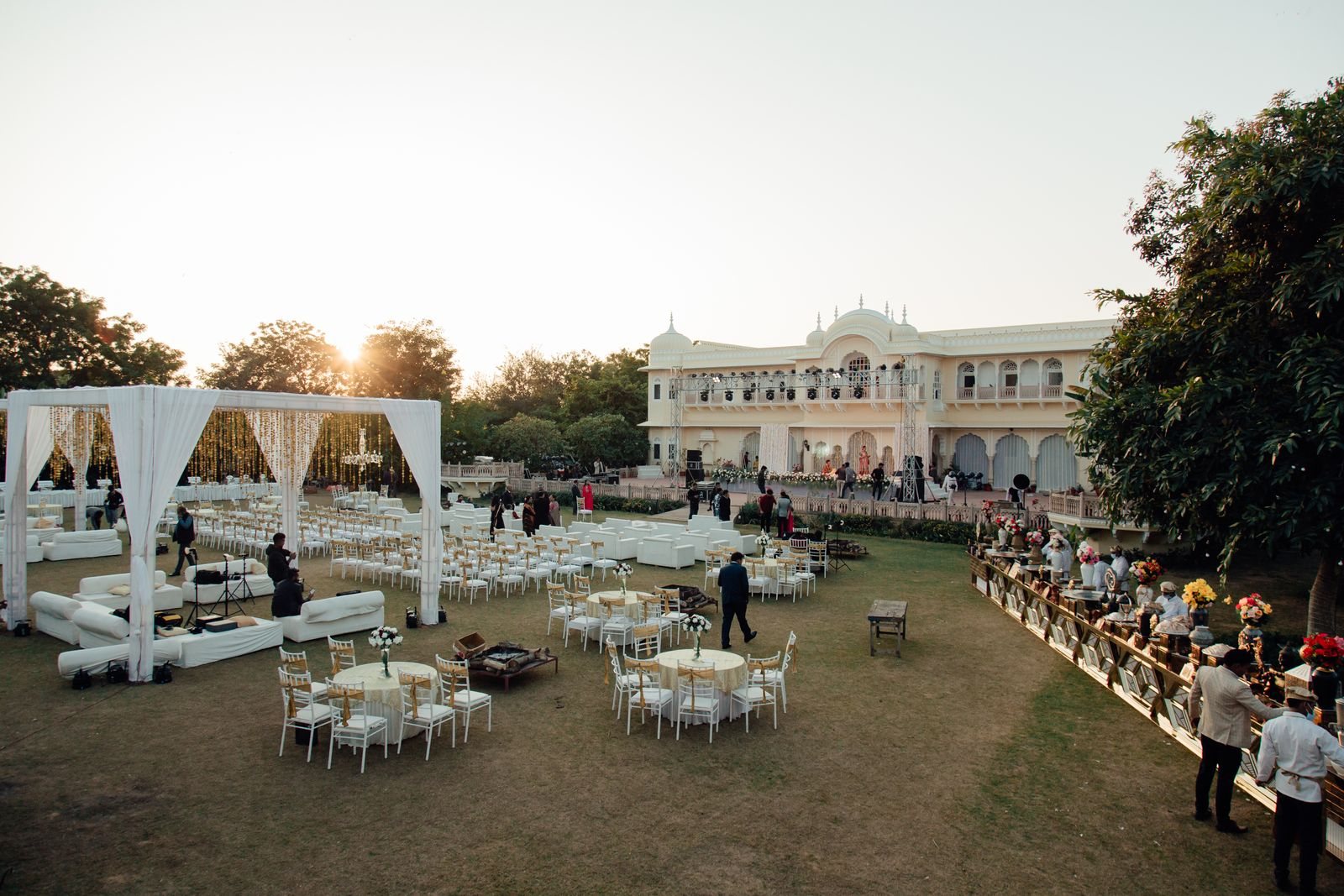An outdoor reception laid with white tables at sunset