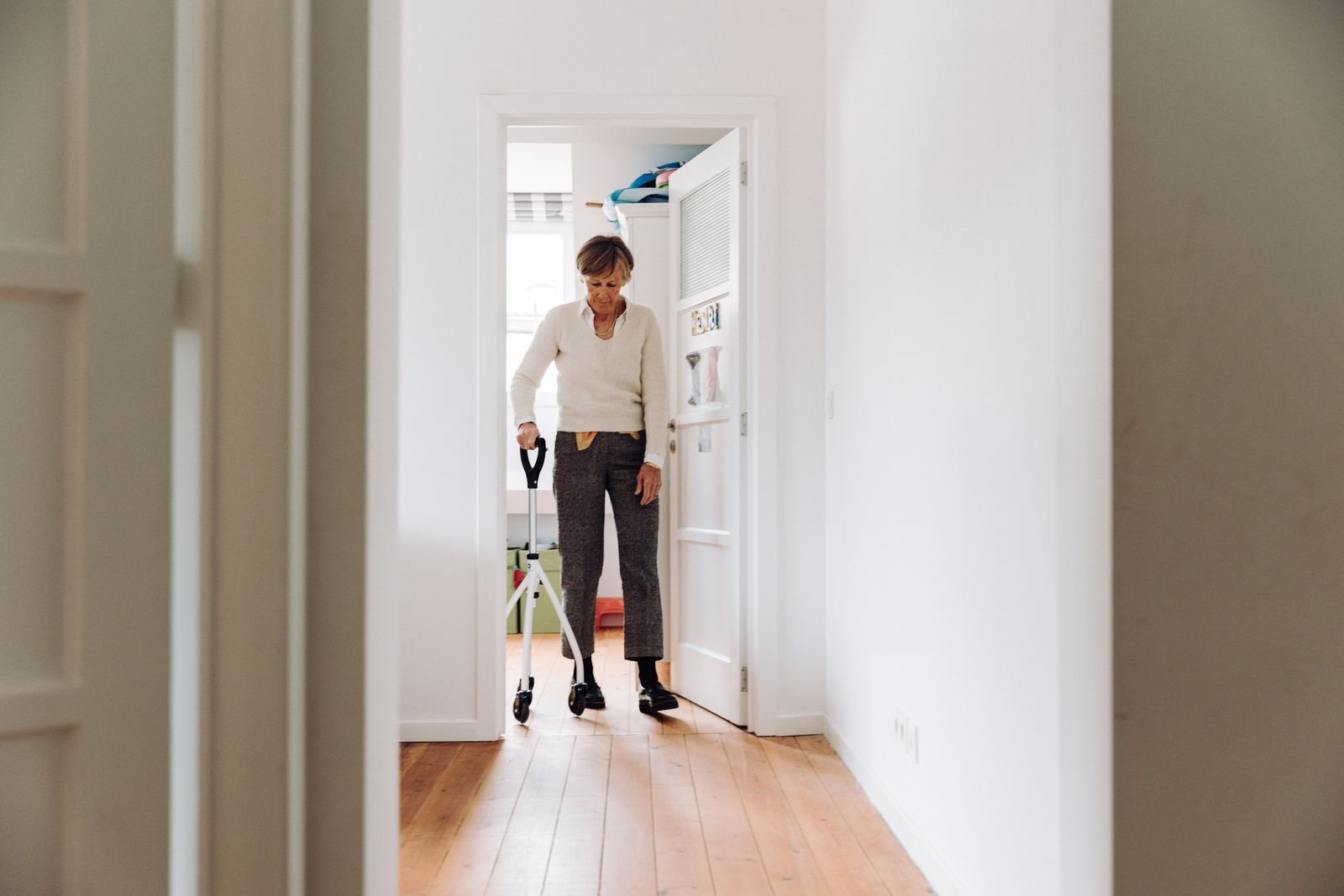 A resident walking with a rollator in a bright hallway