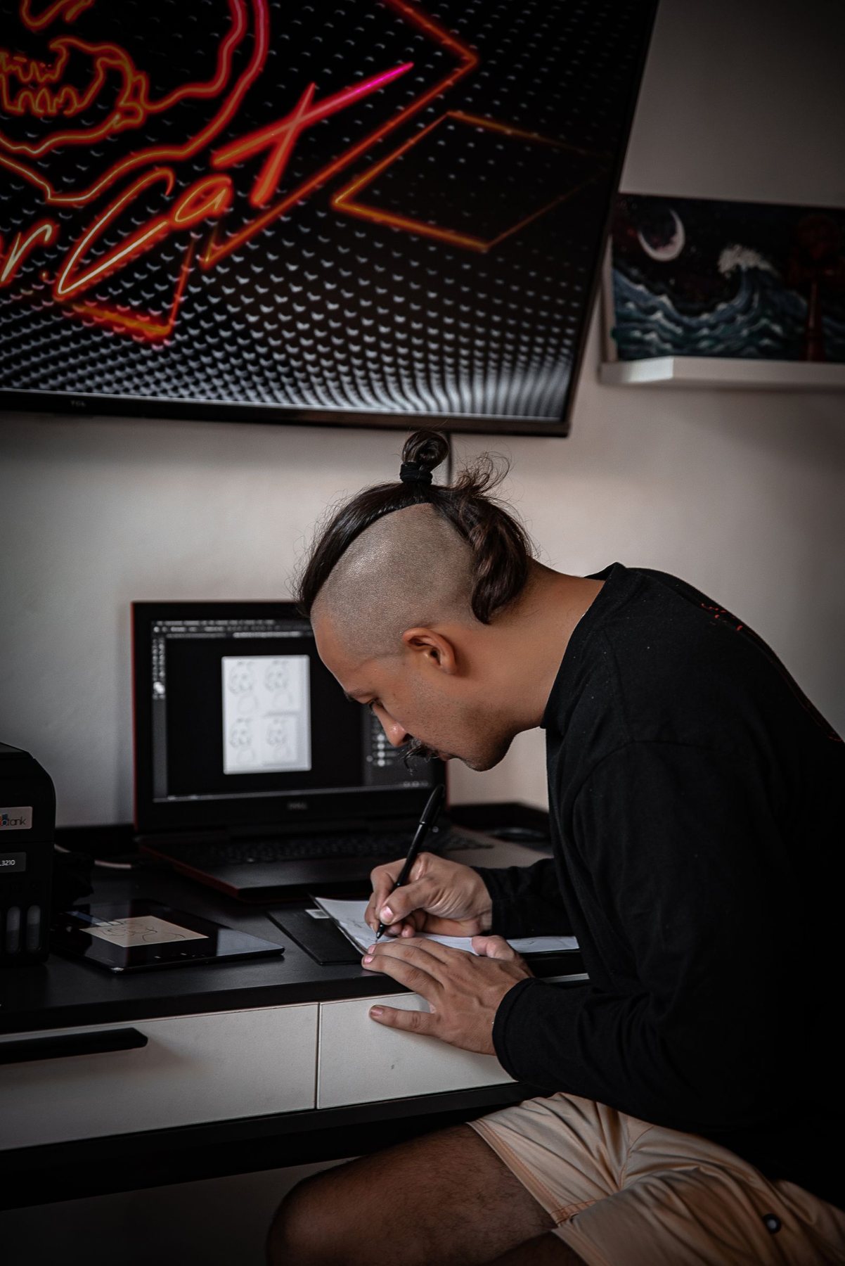 A designer sketching at a desk under neon studio lights