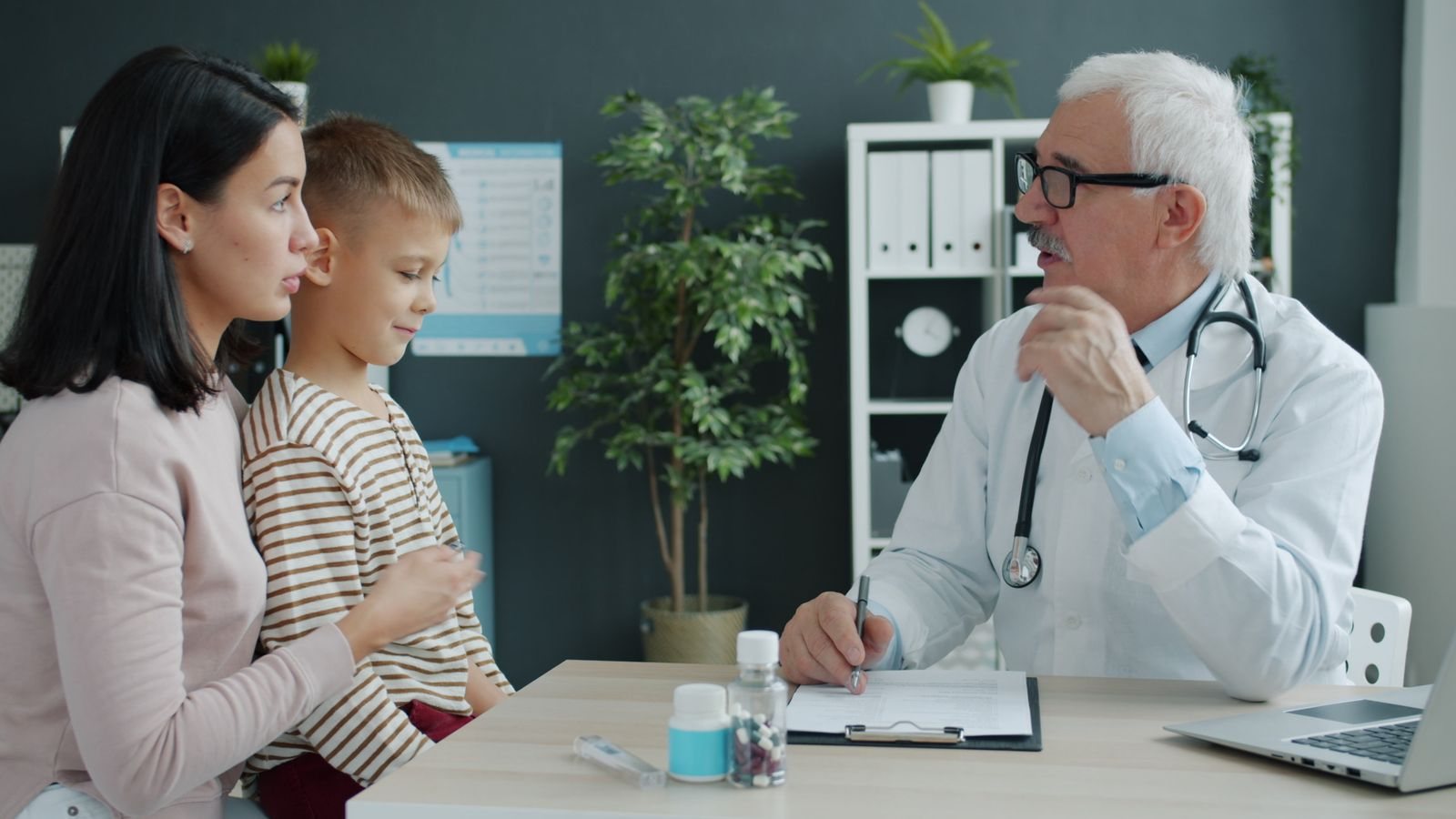 A doctor talking with a mother and her son at a desk