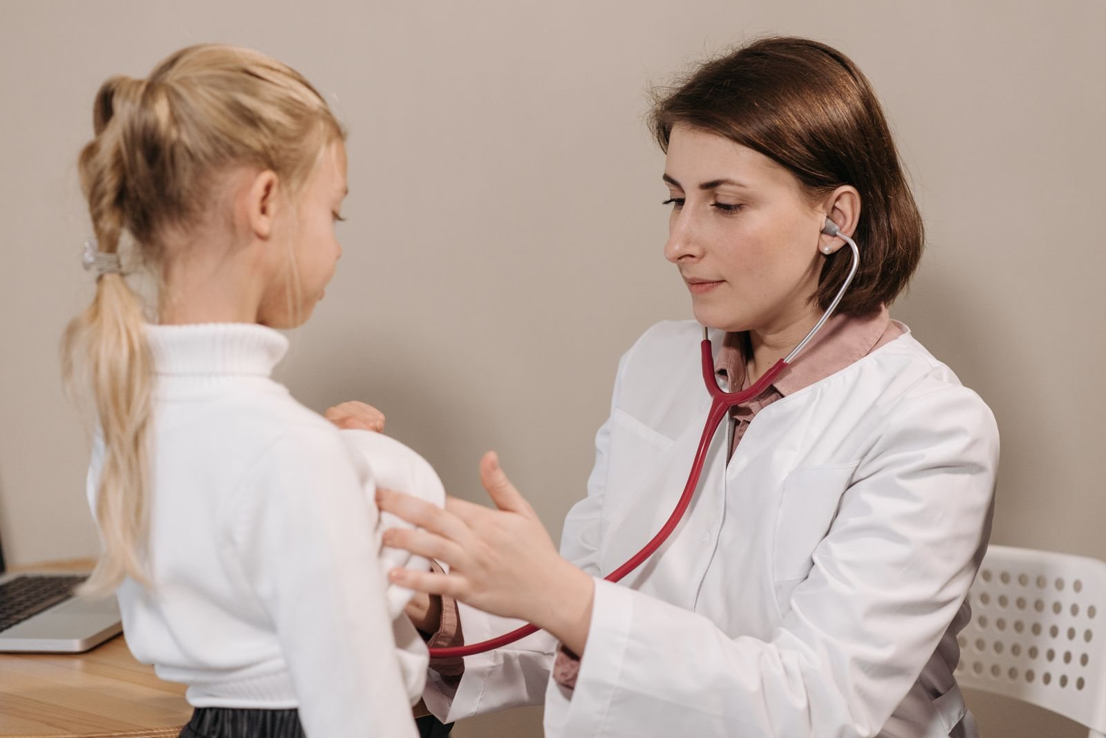 A doctor listening to a girl's breathing with a stethoscope