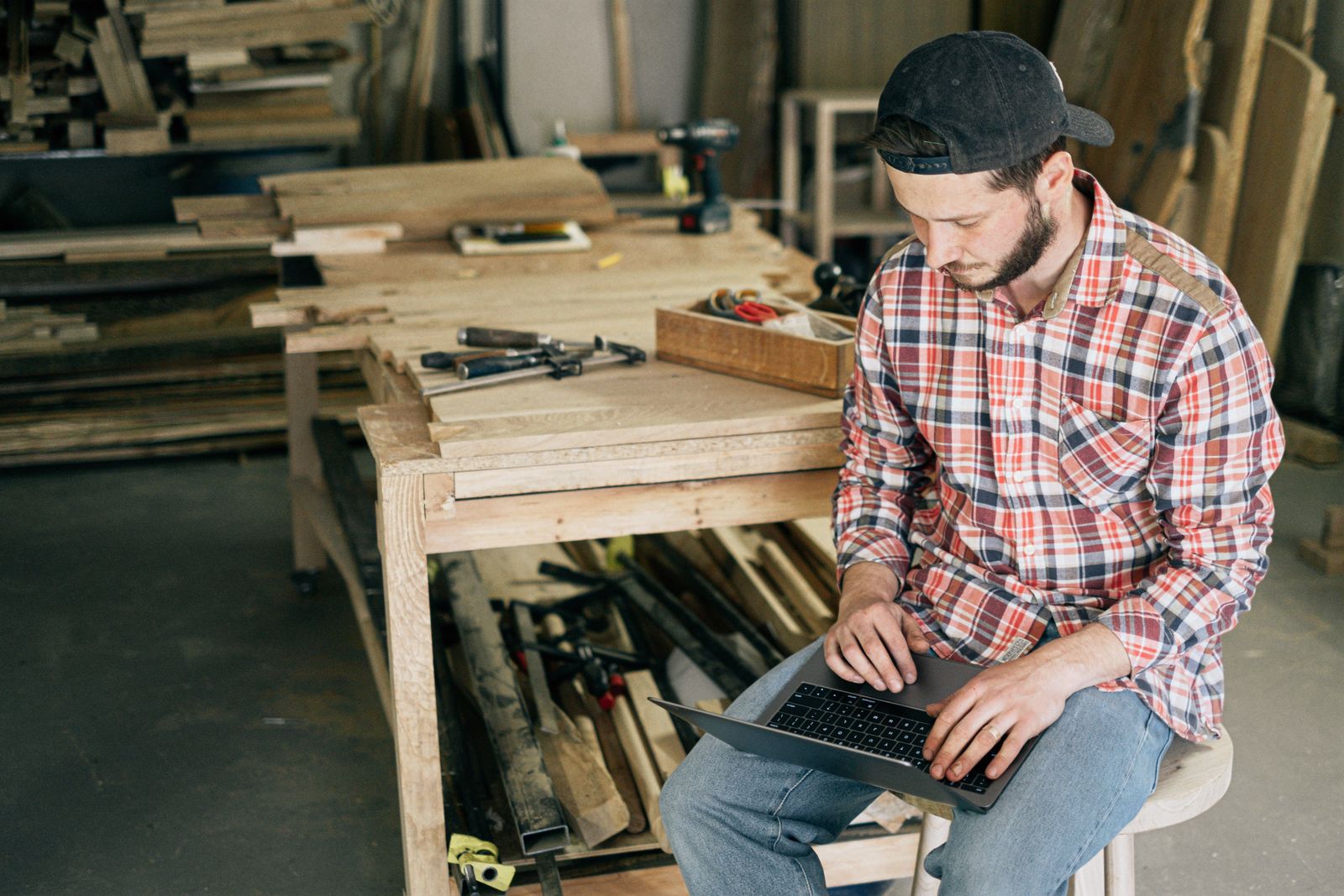 A furniture maker working on a laptop in his workshop