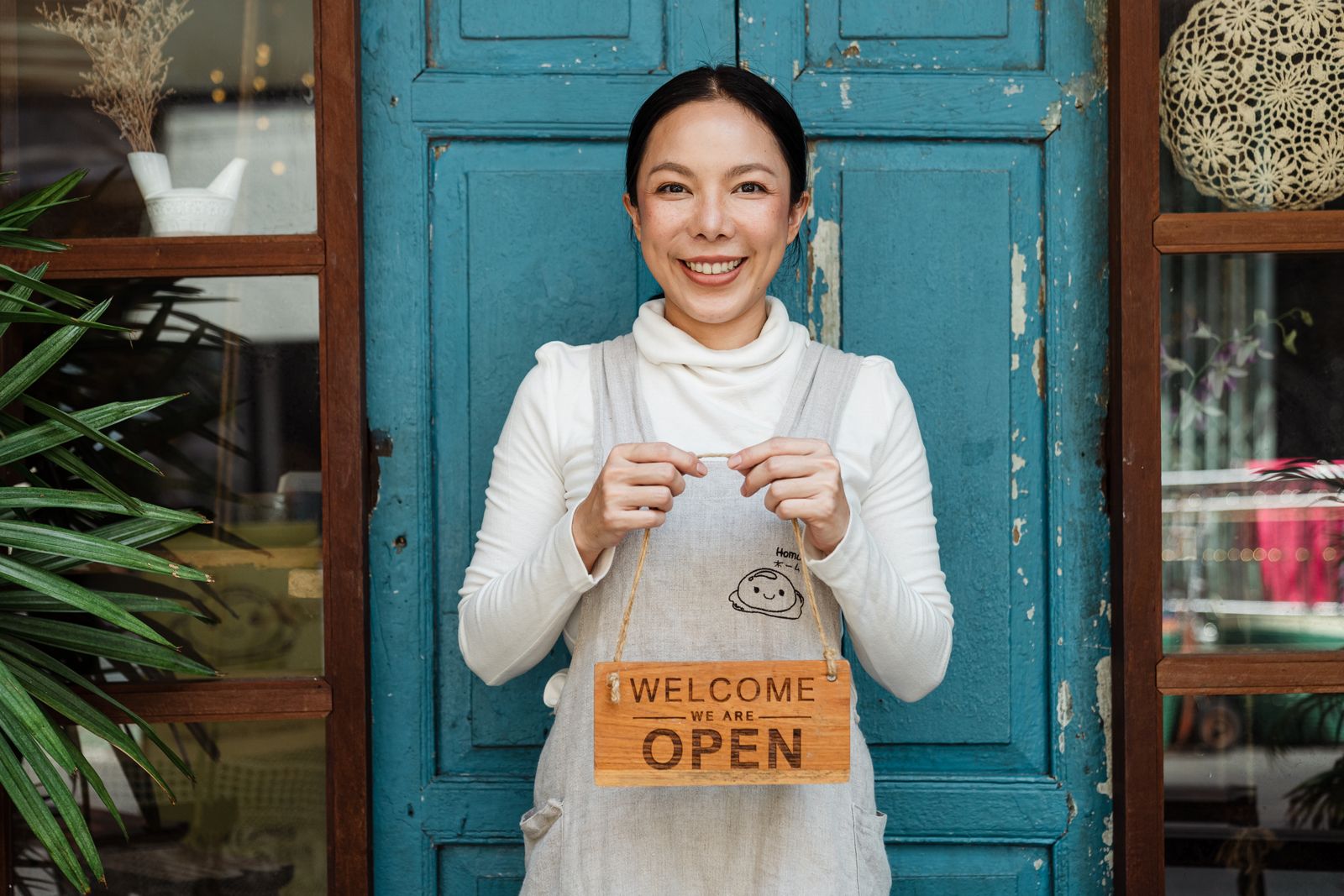 A cafe owner holding a sign that says welcome, we are open