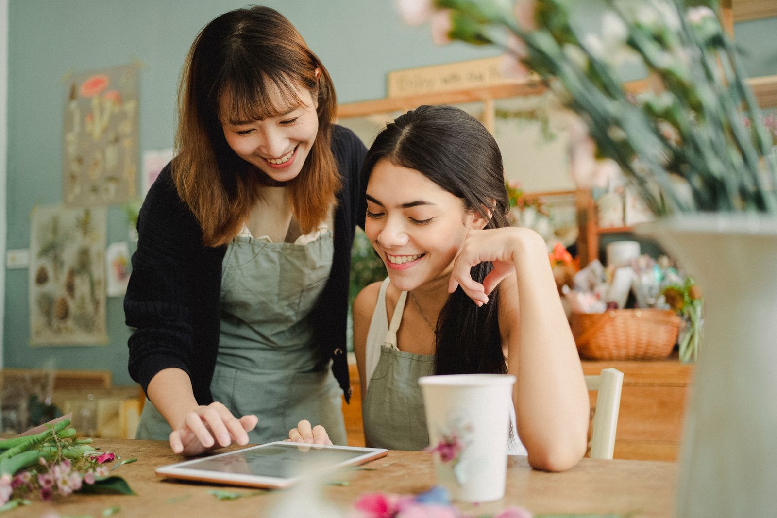 Two florists looking at a tablet together at their workbench