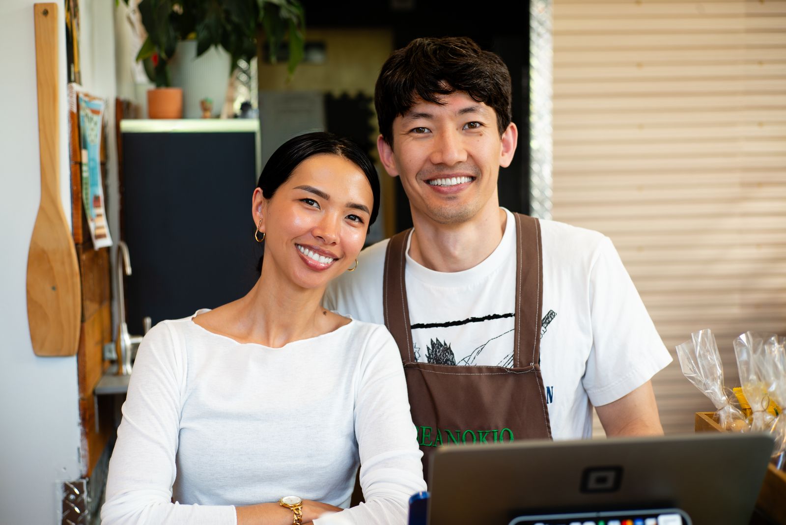 Two owners smiling behind the counter of their shop