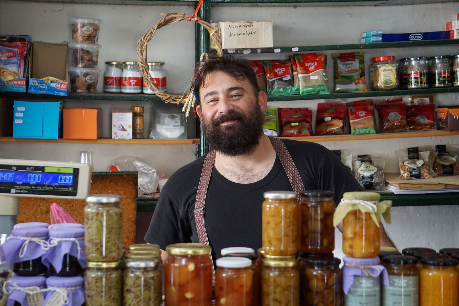 A shopkeeper behind a counter of jars of preserves